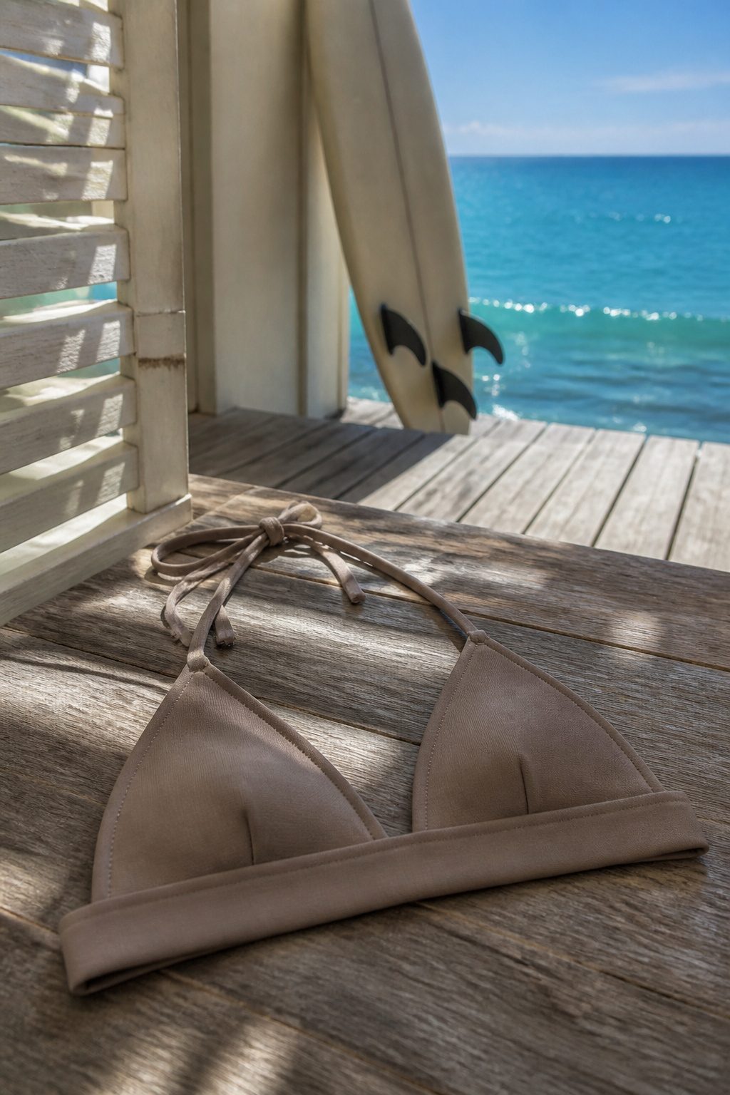 A taupe triangle bikini top displayed on a wooden deck.