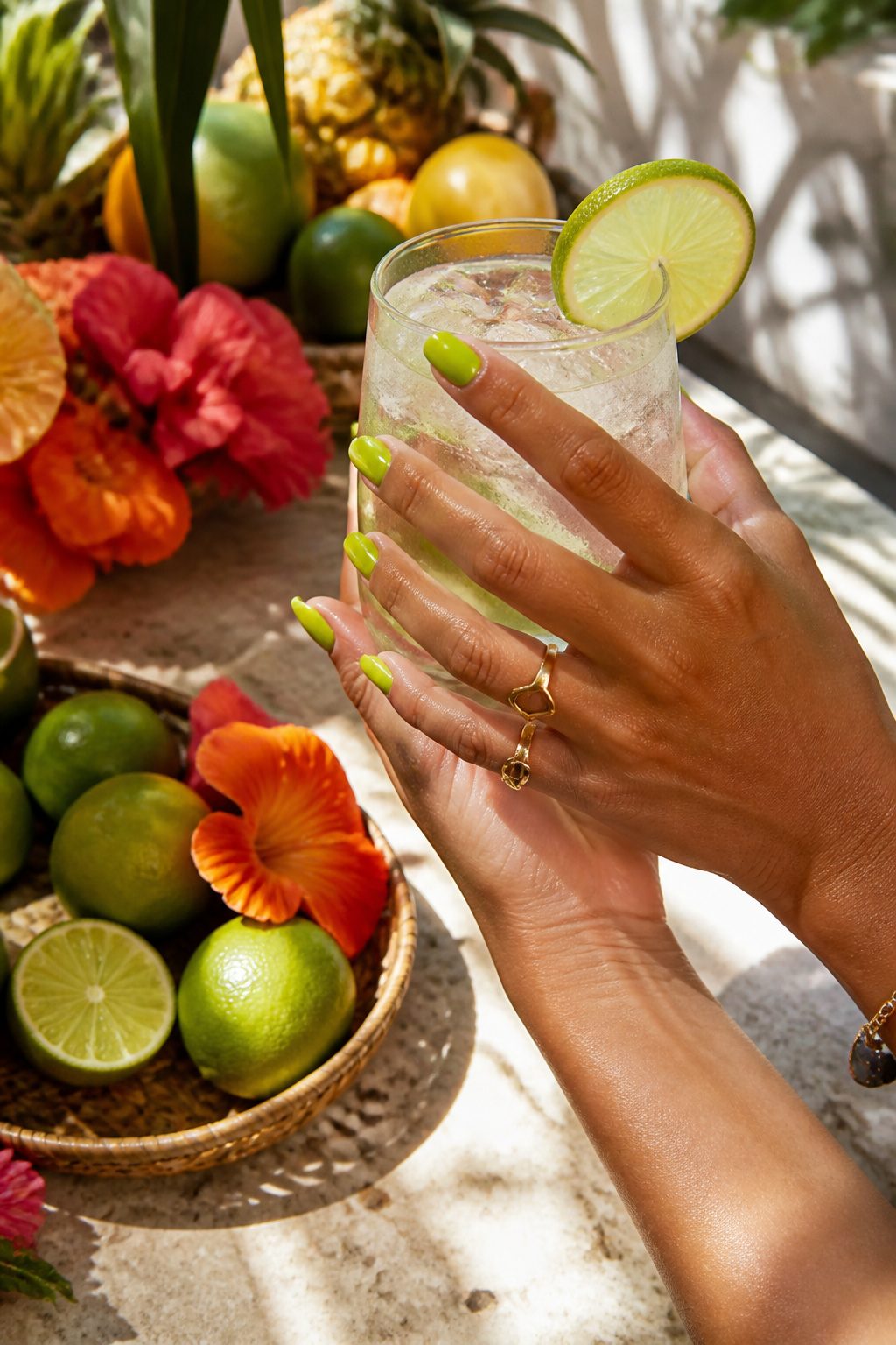 Bright lime green nails holding a drink with citrus.