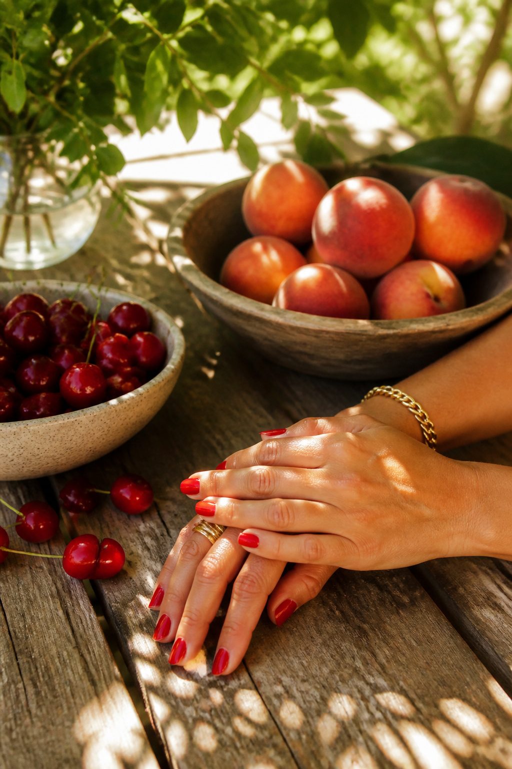 Tomato red nail polish on hands with summer fruits.