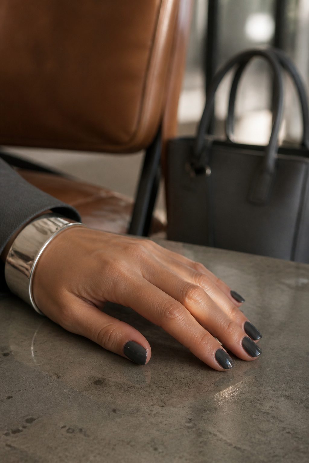 Charcoal grey nails displayed in an office setting.