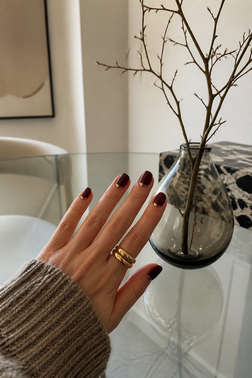Reverse French nails with a metallic accent on a glass table.