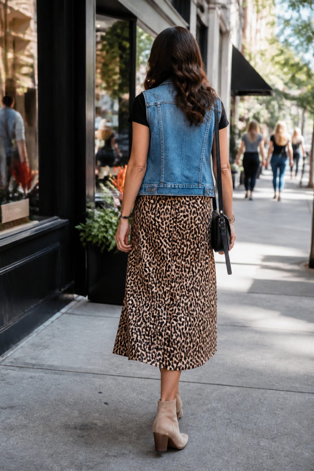 How to Wear a Denim Vest: 13 Outfit Ideas for 2026 11 Model wearing a leopard print skirt and a denim vest in a city block.