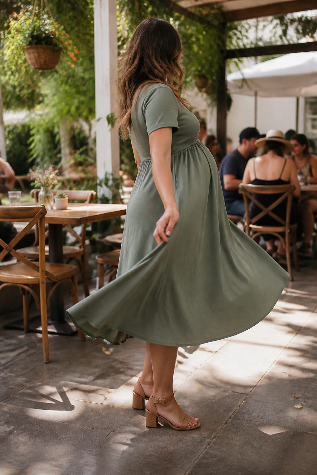 Expectant mother wearing a midi-length dress at a café patio.