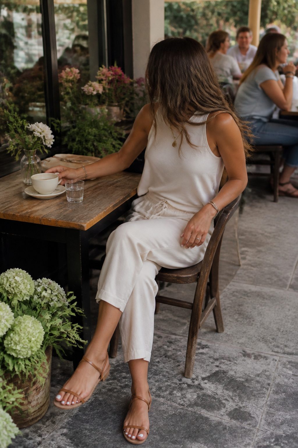 Millennial Mom Outfits: Easy Dressing for Real Days 7 Woman in a sleeveless top and linen pants at a café.