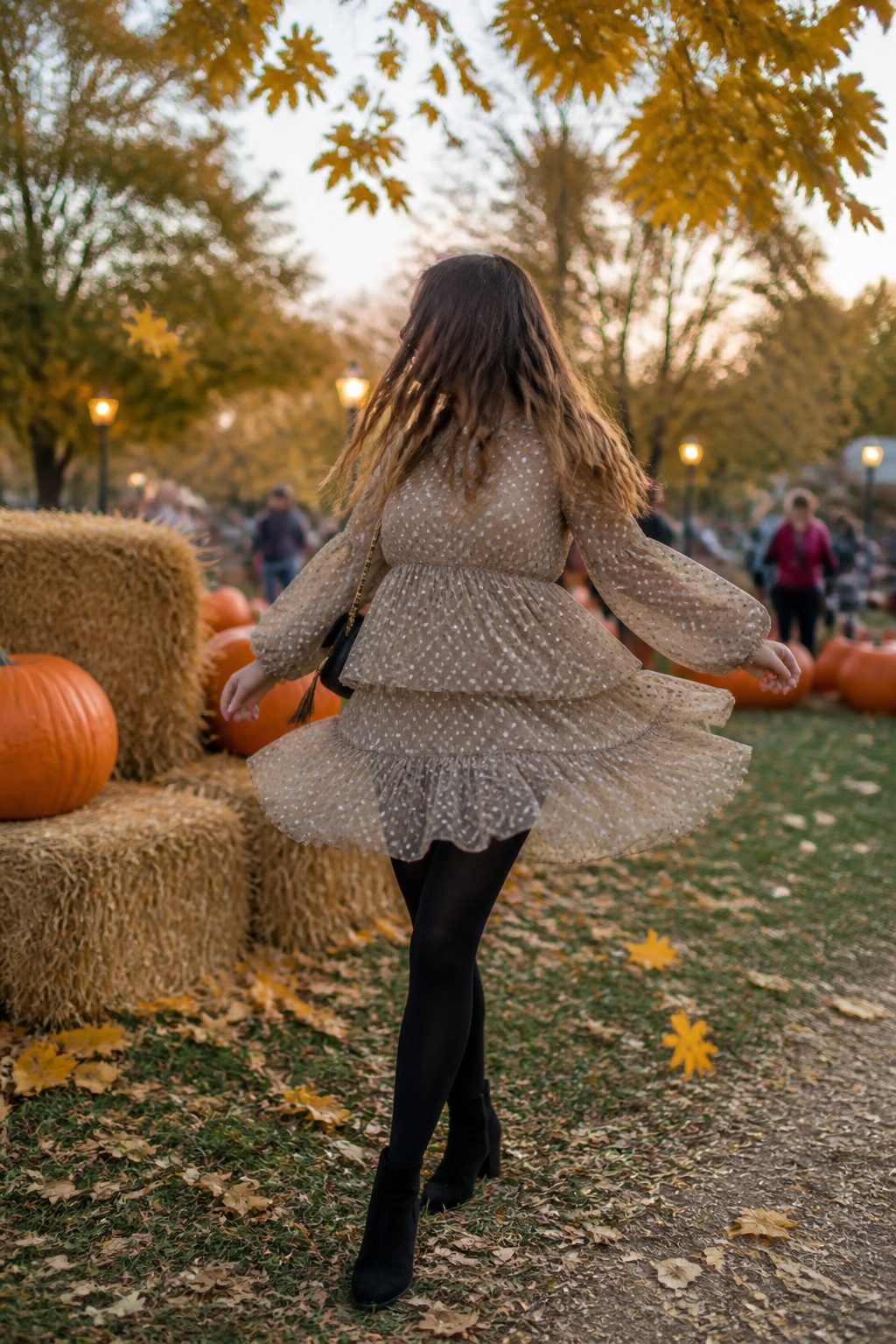 A model in a tiered mini dress and black tights enjoys an autumn festival.