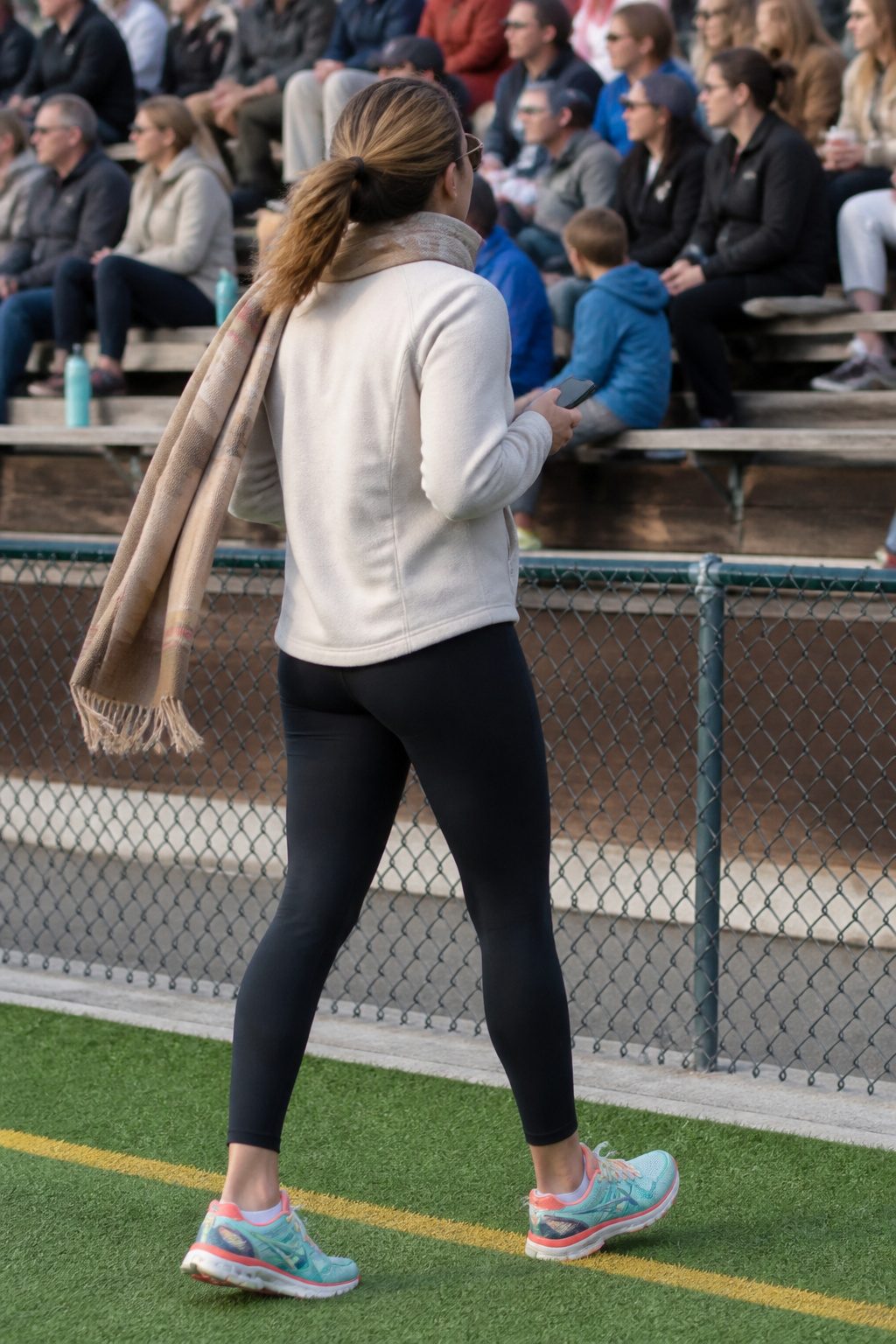 Woman wearing a half-zip pullover and leggings at a soccer field.